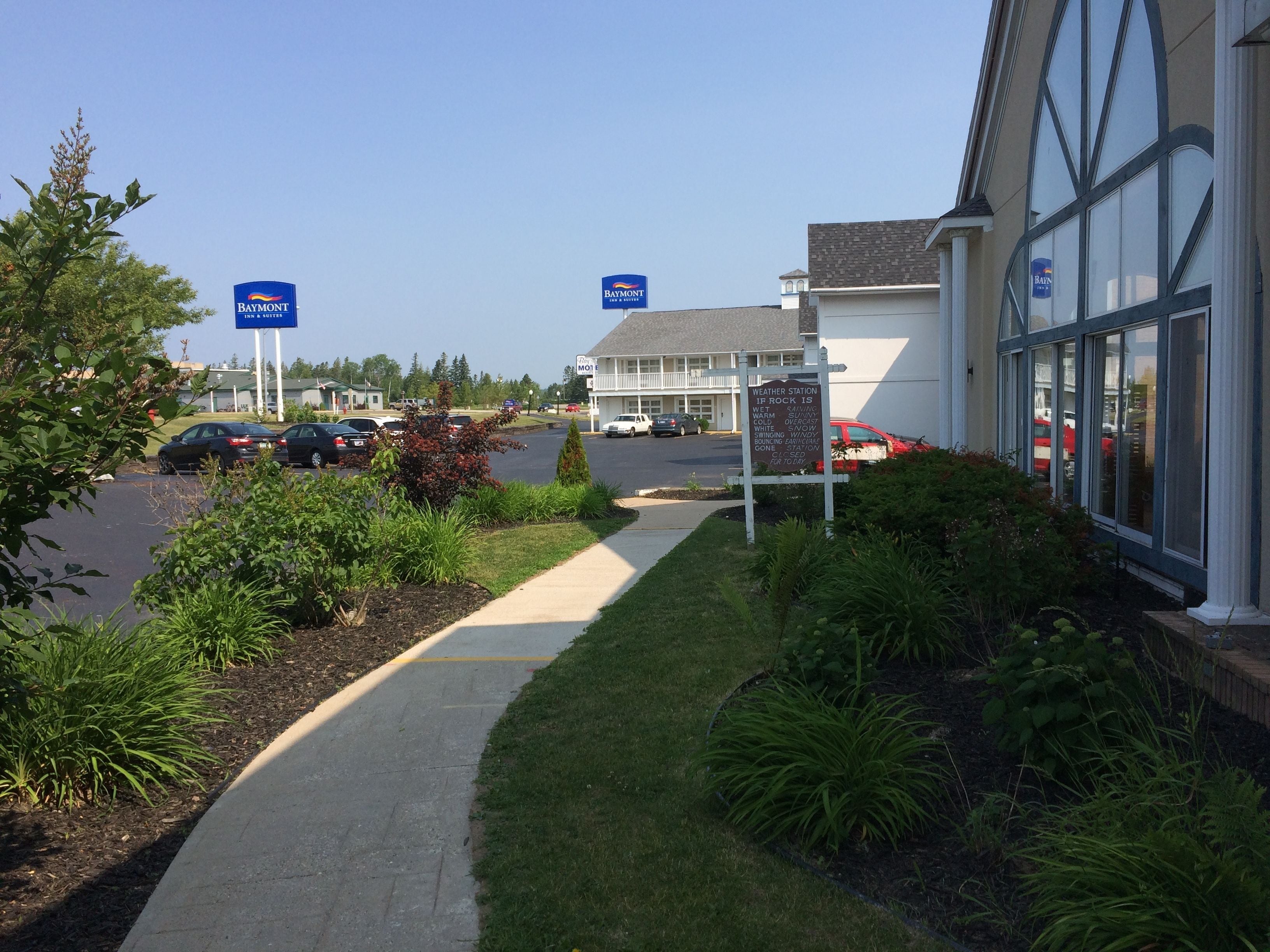 A parking lot with a pathway leading to a building with large windows.