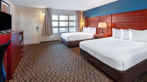 A hotel room with two beds, a TV, a desk, and a window with curtains.