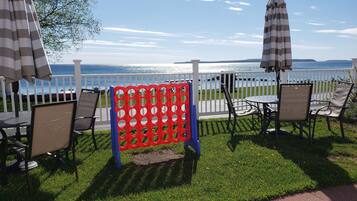An outdoor seating area with chairs and umbrellas, a white fence, and a view of the water.
