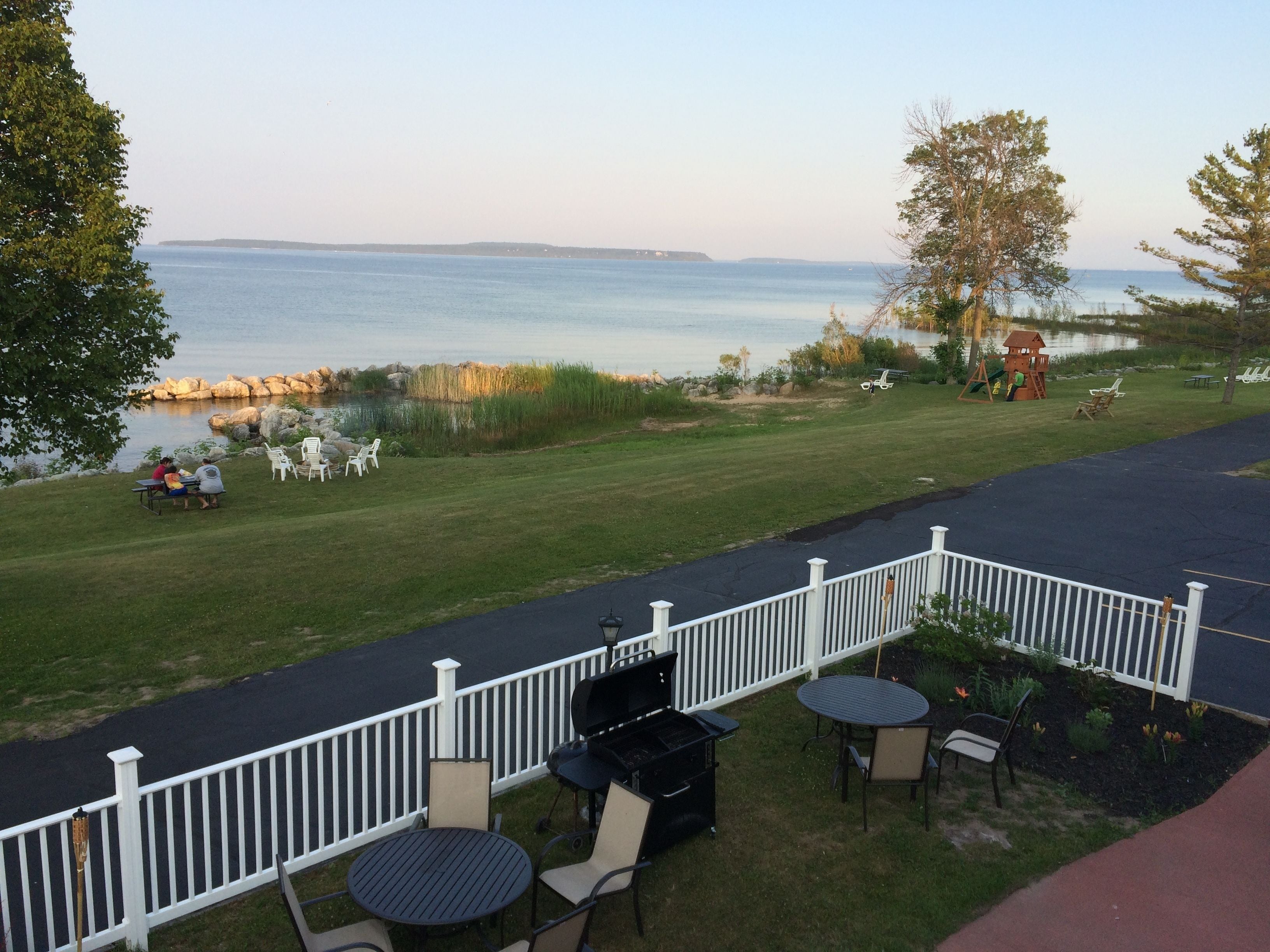 A patio with outdoor seating, a grill, and a view of the water.