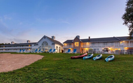 A large hotel with multiple guest rooms, a grassy lawn, and several boats.