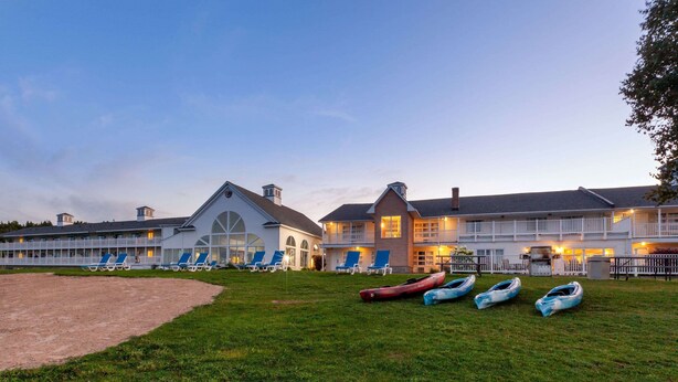 A large hotel with multiple guest rooms, a grassy lawn, and several boats.