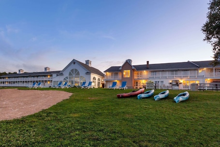 A large hotel with multiple guest rooms, a grassy lawn, and several boats.