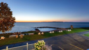 A coastal view with a paved area, lounge chairs, and a picnic table.