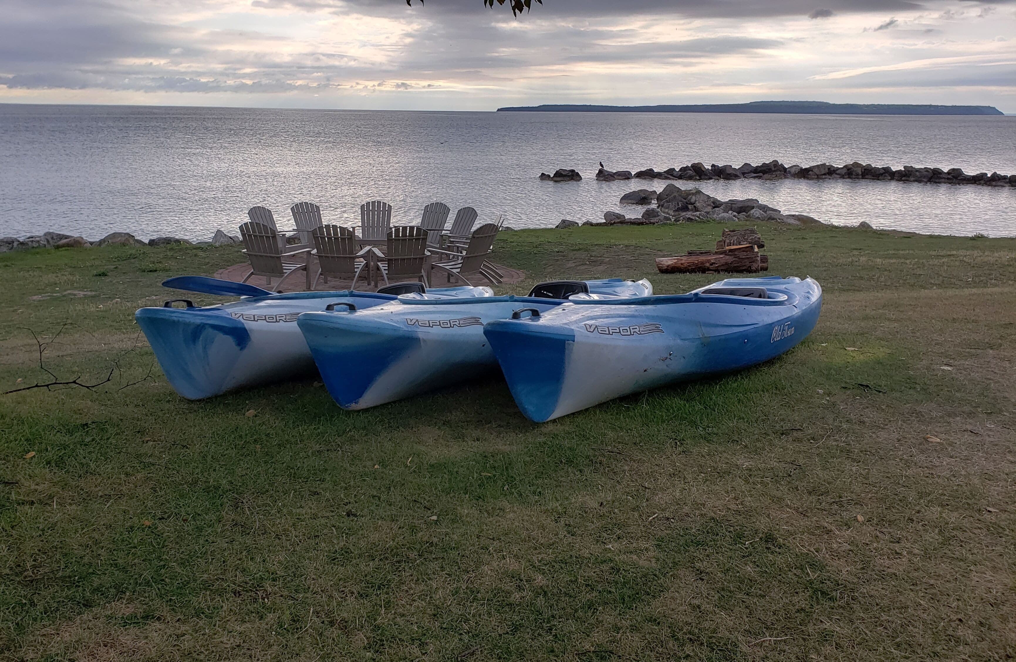Un espacio cubierto de césped con una fila de kayaks azules y blancos con la etiqueta 