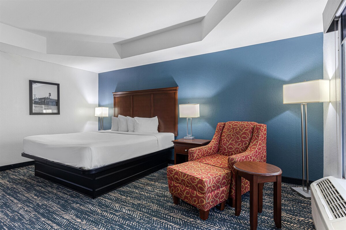 Une chambre d’hôtel avec un grand lit, une chaise, une petite table et une lampe.