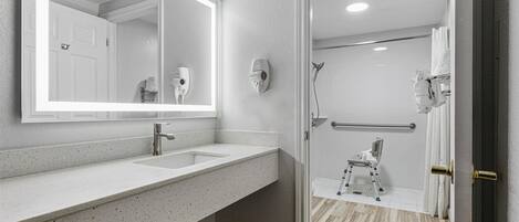 A modern bathroom with a large mirror, a sink, and a shower area.