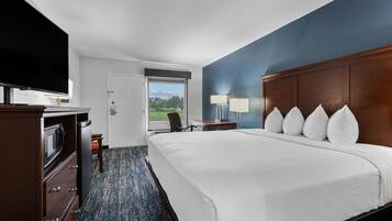 A hotel room with a large bed, a flat-screen TV, a desk, and a chair.