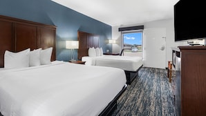Une chambre d’hôtel avec deux lits, une télévision, un bureau et une fenêtre donnant sur un paysage agréable.