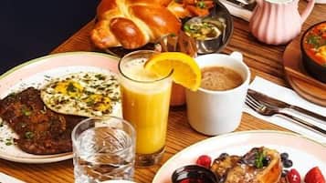Una mesa de desayuno con diferentes platos, incluyendo tortitas, huevos y una taza de café.