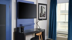 A modern room with a black desk, a chair, a mounted TV, and a framed cityscape picture. - Hotel Victoria (Toronto)