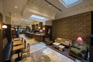 Een ruime loungeruimte met een bar, zitgedeeltes en een decoratieve bloemenwand.