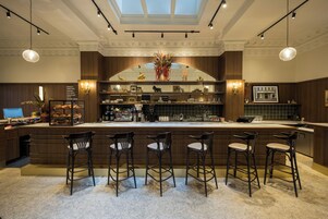 Een bar met een centraal aanrecht, meerdere barkrukken en diverse koffiezetapparatuur.