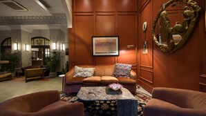 A lobby with a brown leather sofa, two armchairs, a marble coffee table, and a framed painting on the wall. - Hotel Victoria (Toronto)