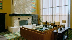 A living room with a stone fireplace, a sofa, a coffee table, and a dining area with chairs and a table.