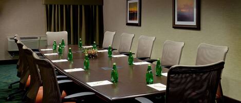 A conference room with a long table, chairs, and green bottles on the table.