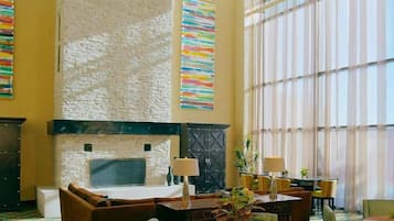 A spacious lobby with a stone fireplace, comfortable seating, and large windows.