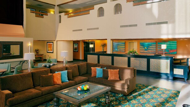 A spacious lobby with a high ceiling, a reception desk, and a seating area with sofas and a coffee table.