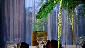 A formal dining table set with white plates, wine glasses, and a centerpiece of greenery and white flowers.