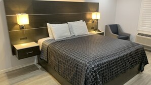 Een moderne hotelkamer met een groot bed, twee bedlampen, een nachtkastje, een stoel en een ingebouwde verwarming.