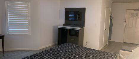 Une chambre à coucher avec un lit, une télévision, une armoire et une fenêtre avec des stores.