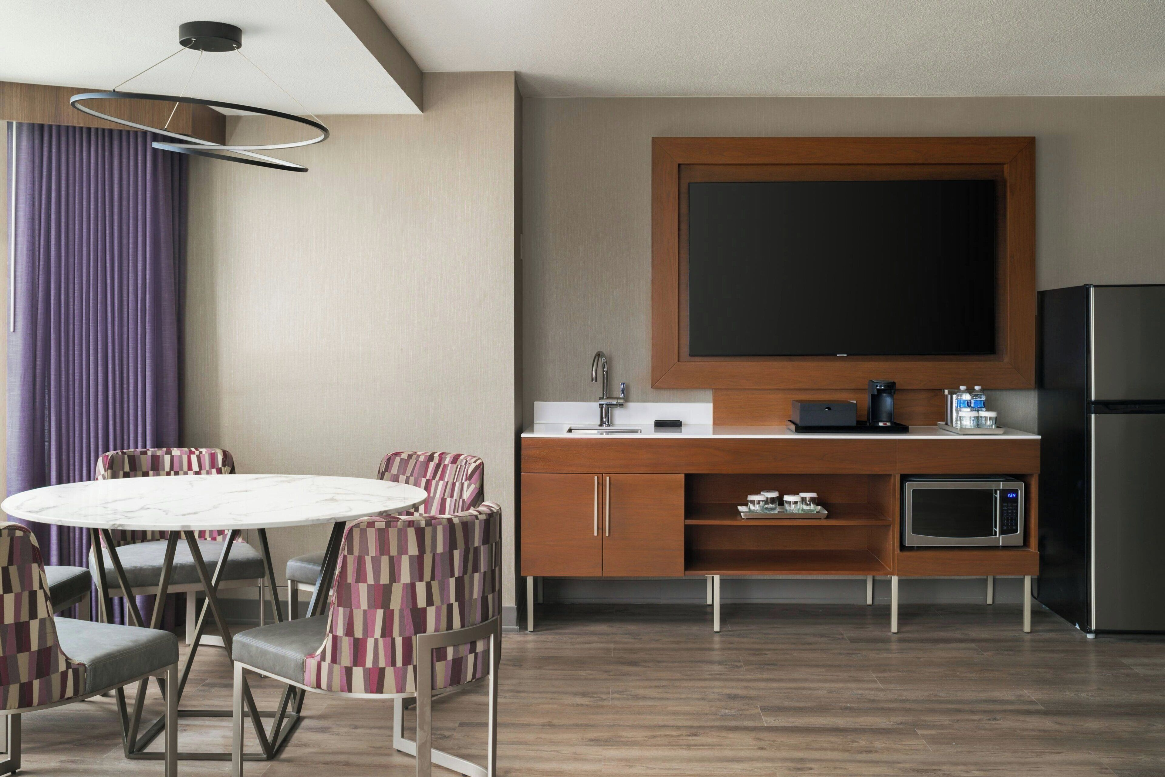 A modern kitchen with a wooden countertop, a built-in microwave, and a stainless steel refrigerator.