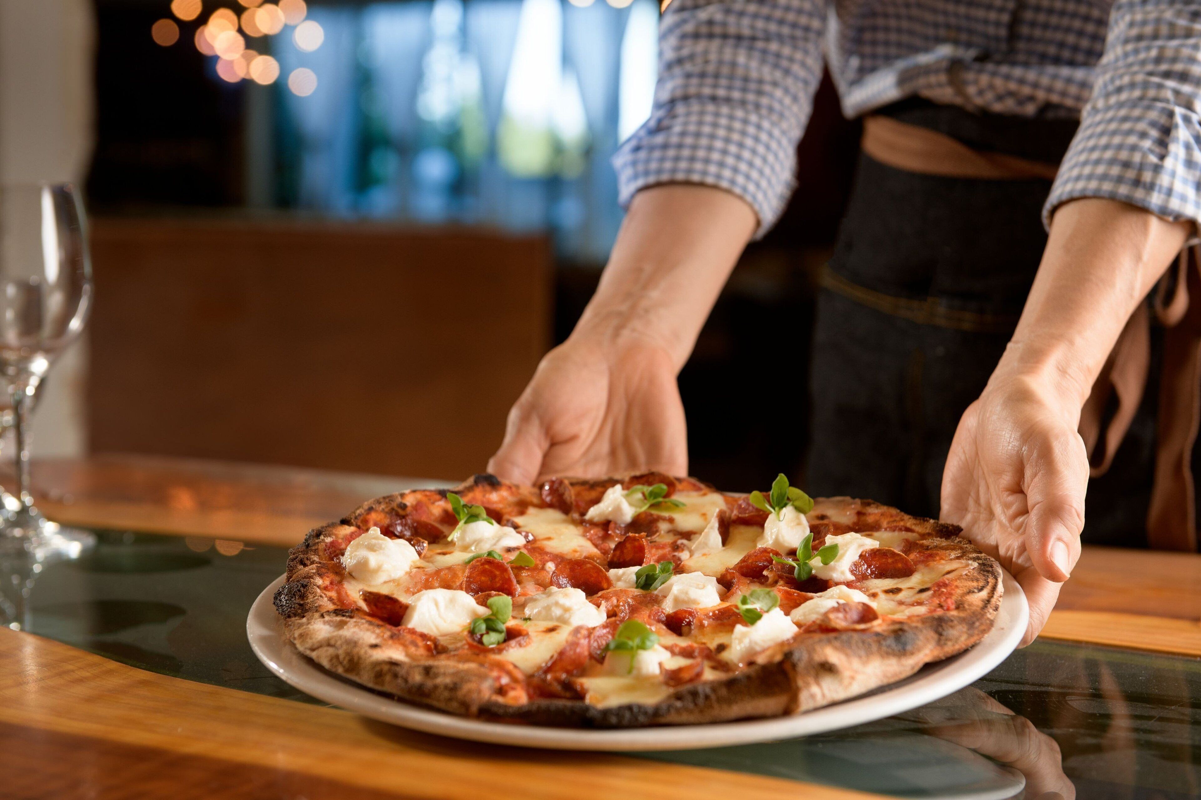 A person serving a pizza on a table.