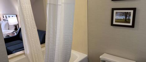 A bathroom with a bathtub, toilet, and a shower curtain. There are two framed pictures on the wall.