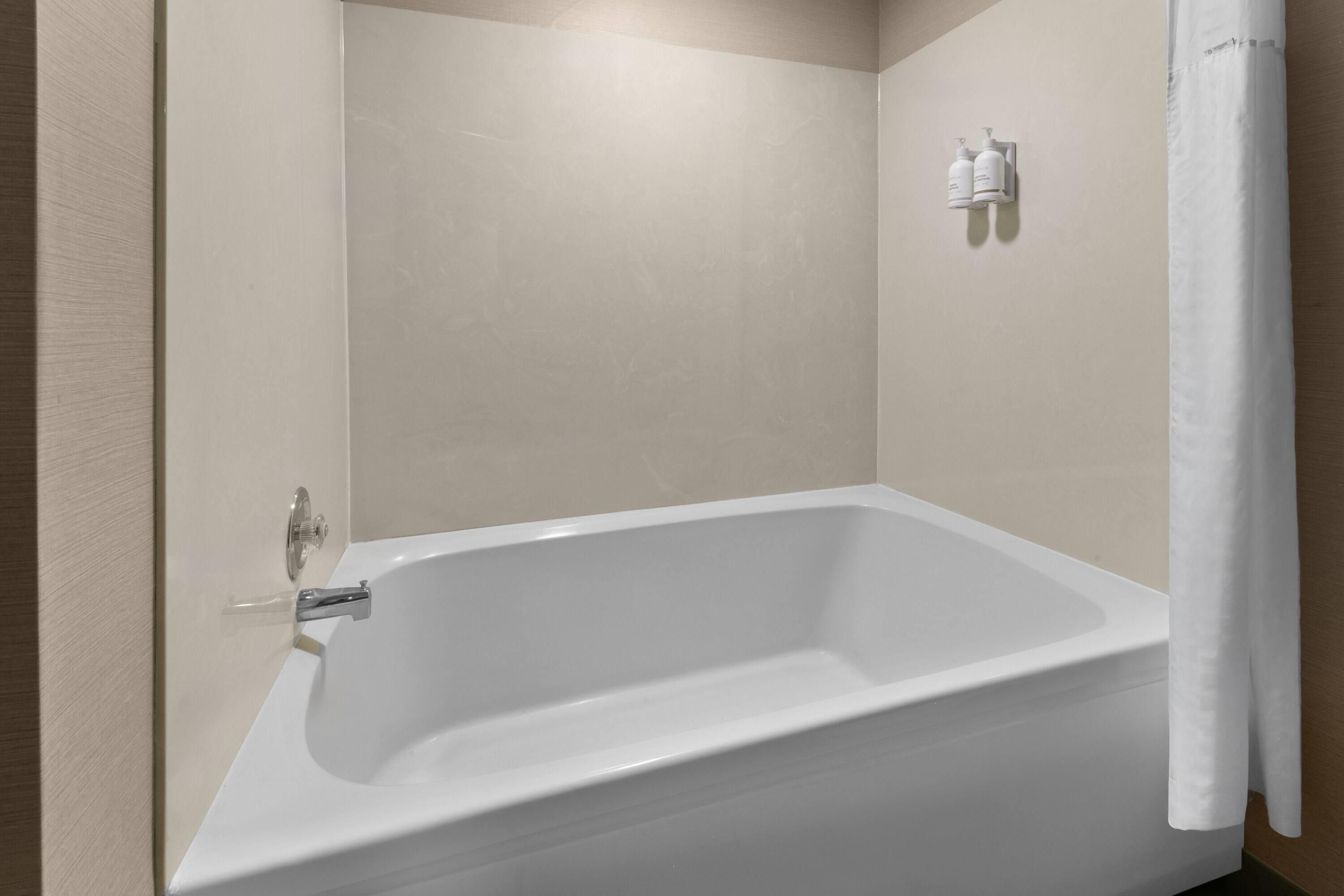 Une salle de bain moderne avec une baignoire sur pieds, un rideau de douche et un sèche-mains fixé au mur.