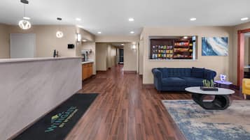 A hotel lobby with a reception desk, a sofa, a coffee table, and a snack display.
