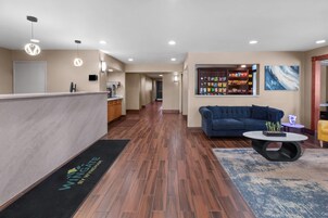Um saguão de hotel com balcão de recepção, um sofá, uma mesa de centro e uma mesa com petiscos.