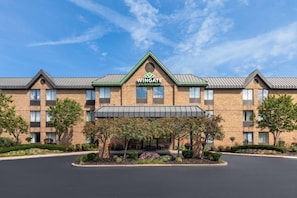 A hotel with a brick facade, a green roof, and a covered entrance.
