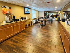 Un restaurant spacieux doté d’un plancher en bois, d’une salle à manger centrale et d’un comptoir de cuisine équipé de divers appareils.