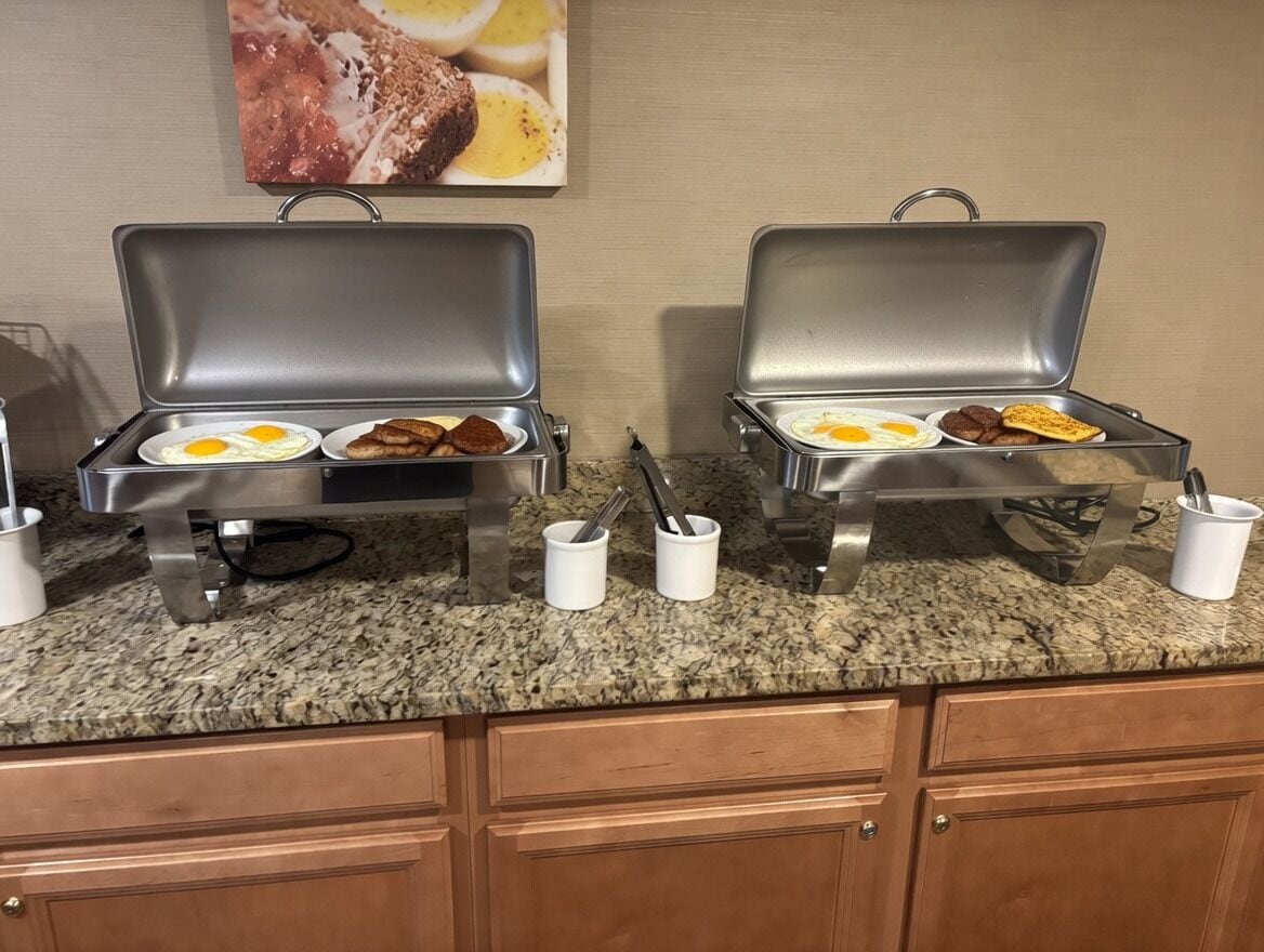 Two portable grills with food items on a granite countertop.