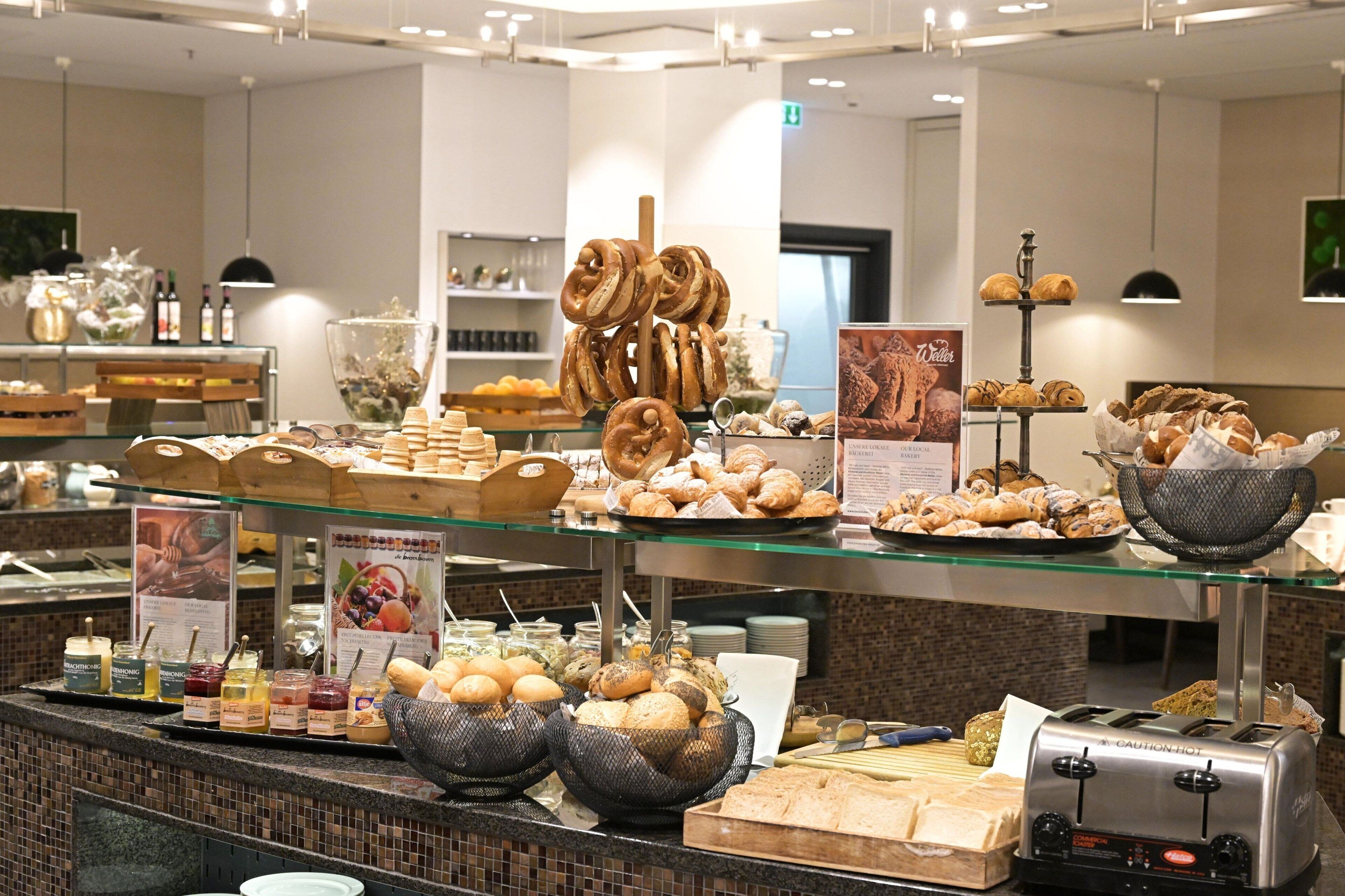 A buffet with various baked goods, including pastries and breads, and a toaster.