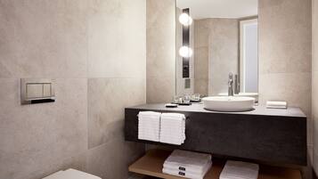 A modern bathroom with a large mirror, a round sink, and a toilet.