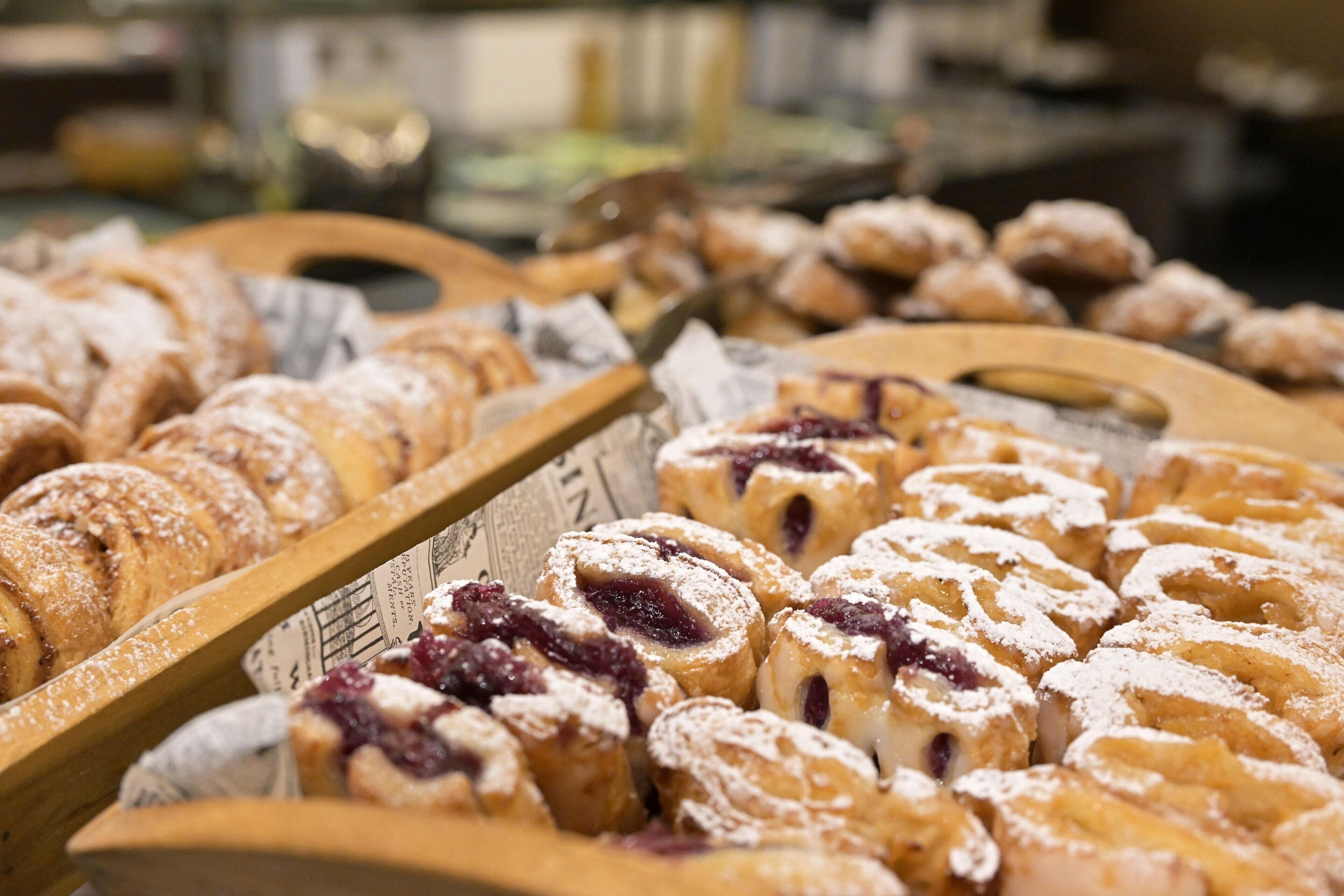 A display of pastries, including croissants and danishes, arranged on trays.