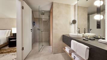 Een moderne badkamer met een douche met glazen wand, twee wasbakken en een grote spiegel.