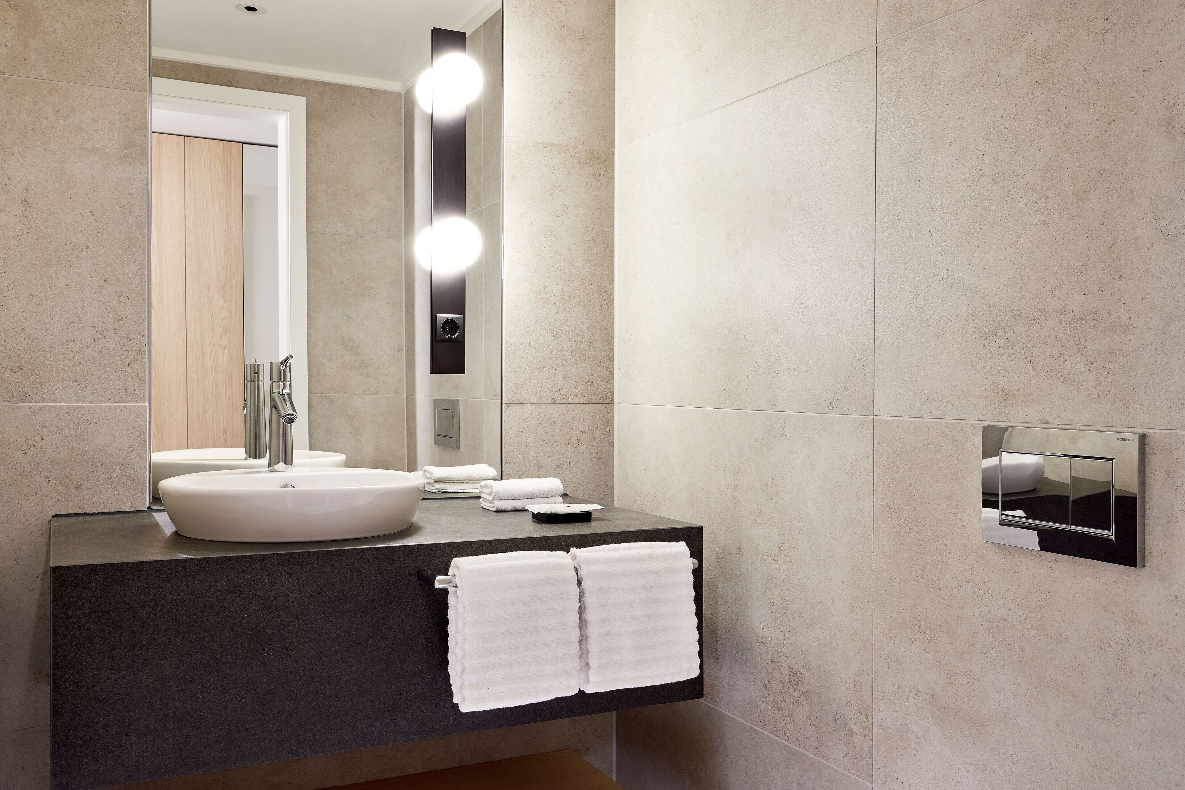 A modern bathroom with a large mirror, a sink, and a towel rack.