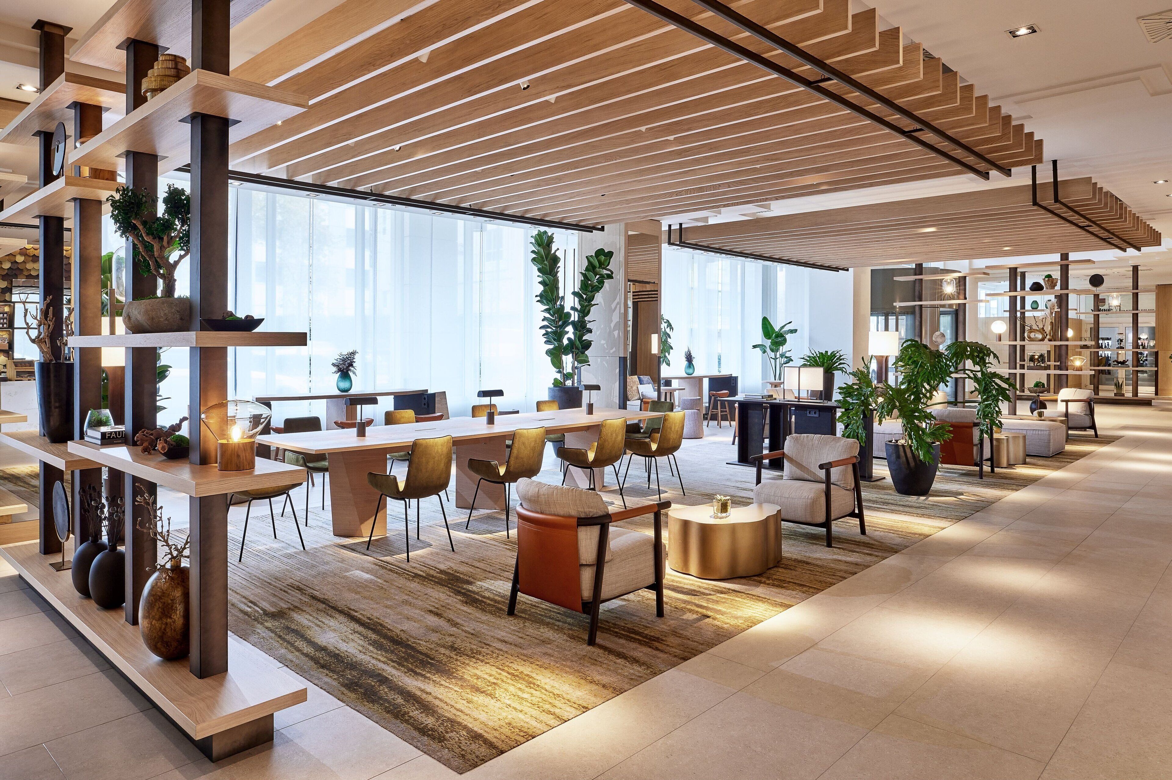 Eine geräumige, moderne Hotelhalle mit einer langen Rezeption, gemütlichen Sitzbereichen und einem großen Fenster, das für natürliches Licht sorgt.