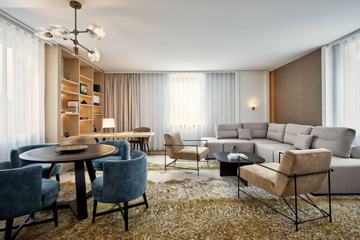 A modern living room with a sofa, armchairs, a coffee table, and a dining area with chairs and a table.
