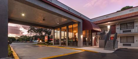 Hotel con un área exterior techada, una escalera y un estacionamiento.