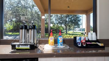A coffee station with a coffee machine, two bottles of coffee creamer, and a box of creamer.