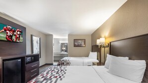 A hotel room with a bed, a TV, a desk, and a dresser.