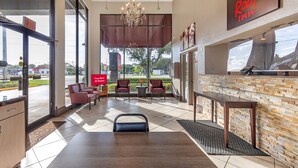 A hotel lobby with a reception desk, seating area, and a view of the outdoors.