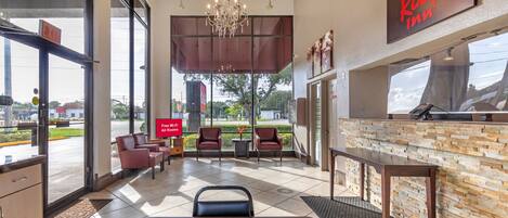 Un hall de hotel con una recepción, zona de estar y vistas al exterior.