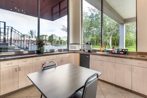 A modern kitchen with a dining table, cabinets, and a view of the street and trees outside. - Red Roof Inn Ft Pierce (Fort Pierce)