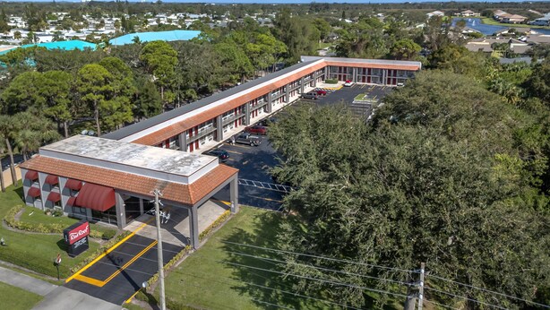 A multi-story building with a flat roof, parking lot, and a Red Roof sign.