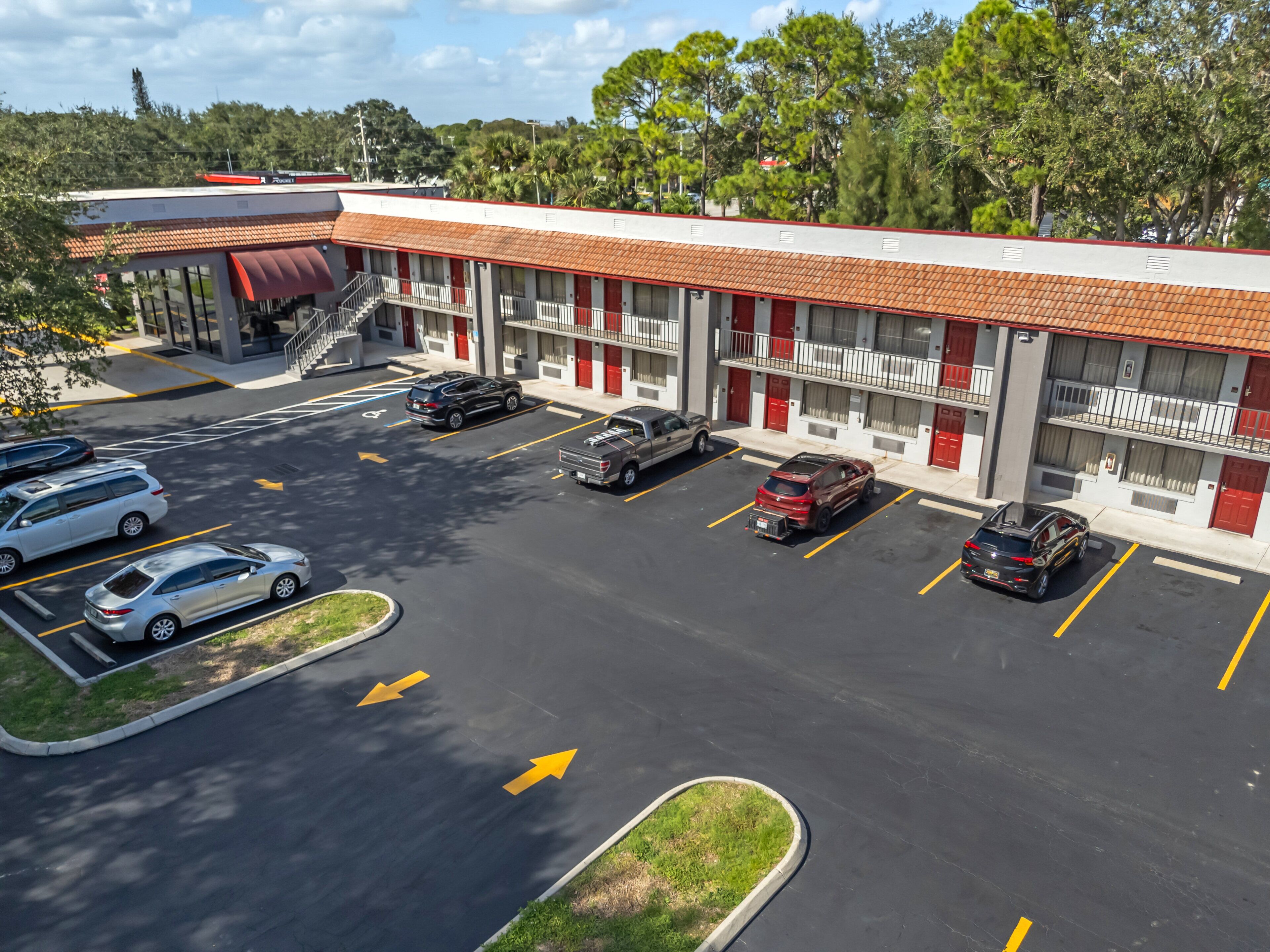 Un motel à la façade rouge et blanche, doté de nombreux espaces de stationnement et d’une allée couverte.