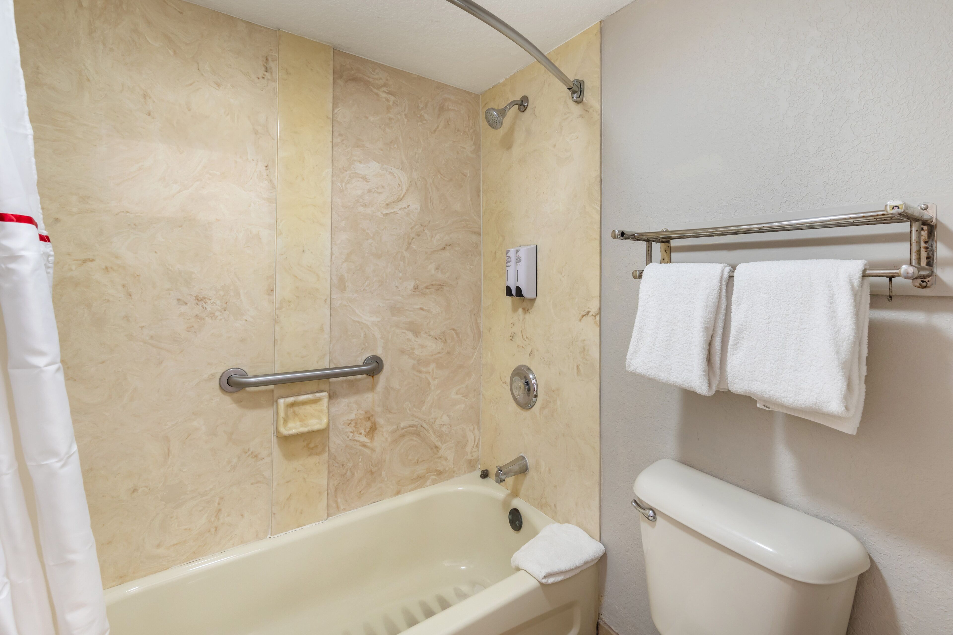 Un baño con bañera, inodoro, ducha y un perchero para toallas.